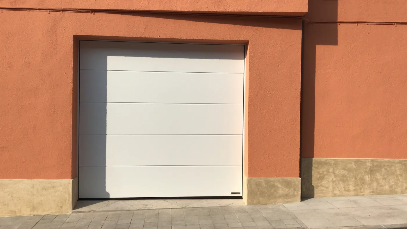 Porta de garatge seccional blanca instal·lada en un habitatge