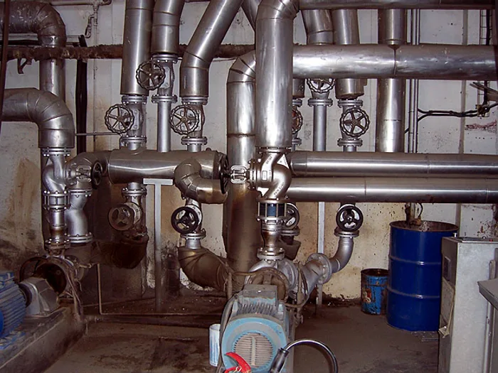 Sala de màquines amb canonades d'acer inoxidable i vàlvules, en una instal·lació industrial d'Instal Jet