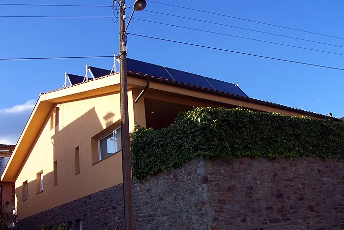 Plaques solars a la teulada d'una casa de color groc